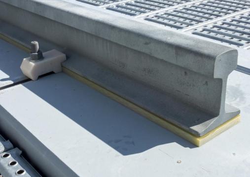 TRANSFORMER RAIL WITH GLASS-TEXTILE PAD AND PVC CLAMP ON A CONCRETE THRESHOLD.